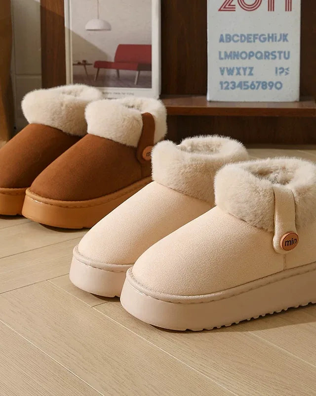 Ivory white and dark brown slipper boots side by side on a wooden floor