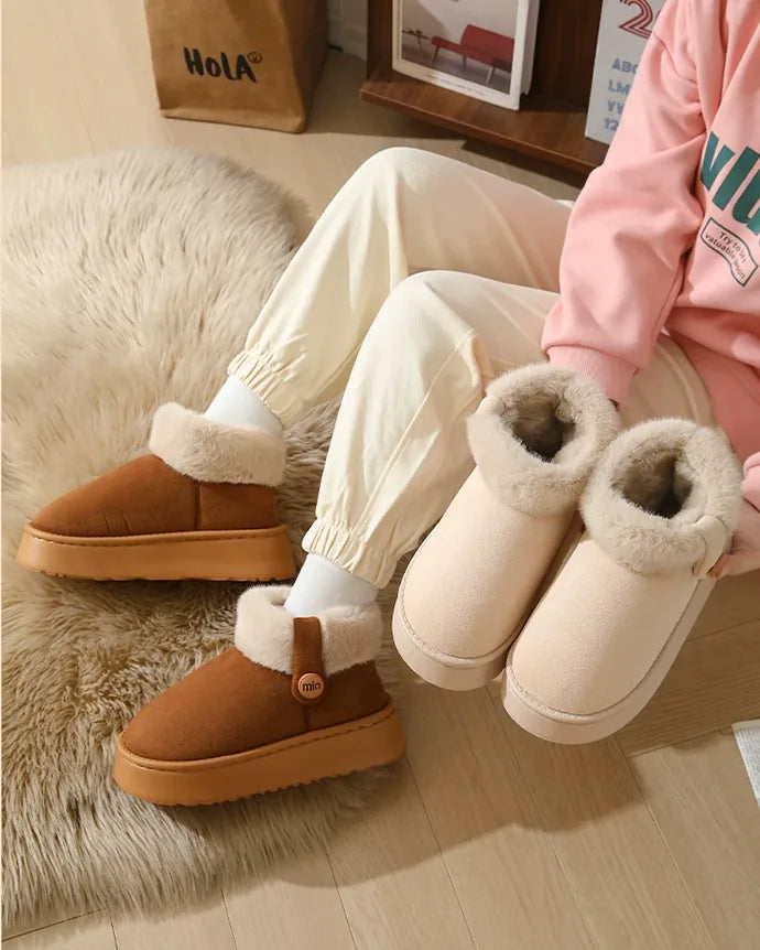 Someone sitting on a rug wearing dark brown boots, with an ivory white pair beside them